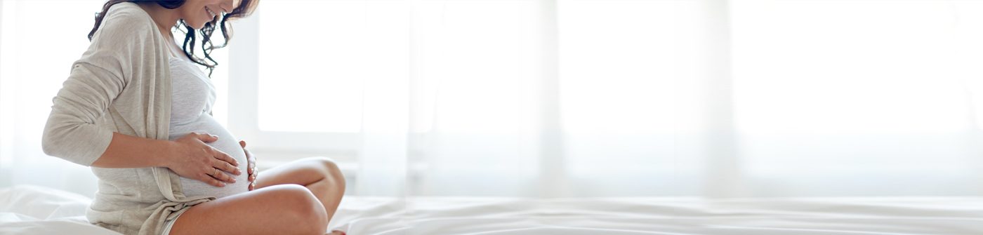 Pregnant female patient sitting on bed